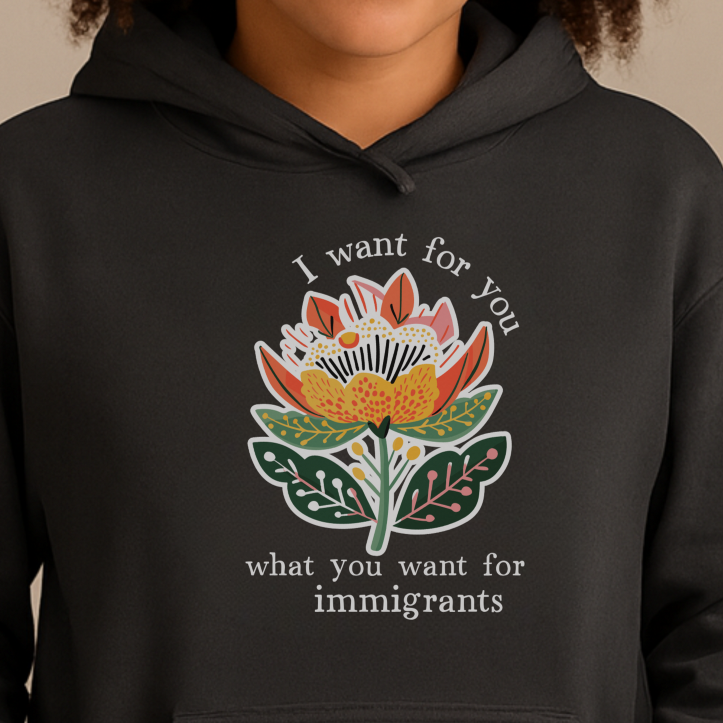 Person wearing a pro-immigration black hoodie with a floral design and text on a beige background