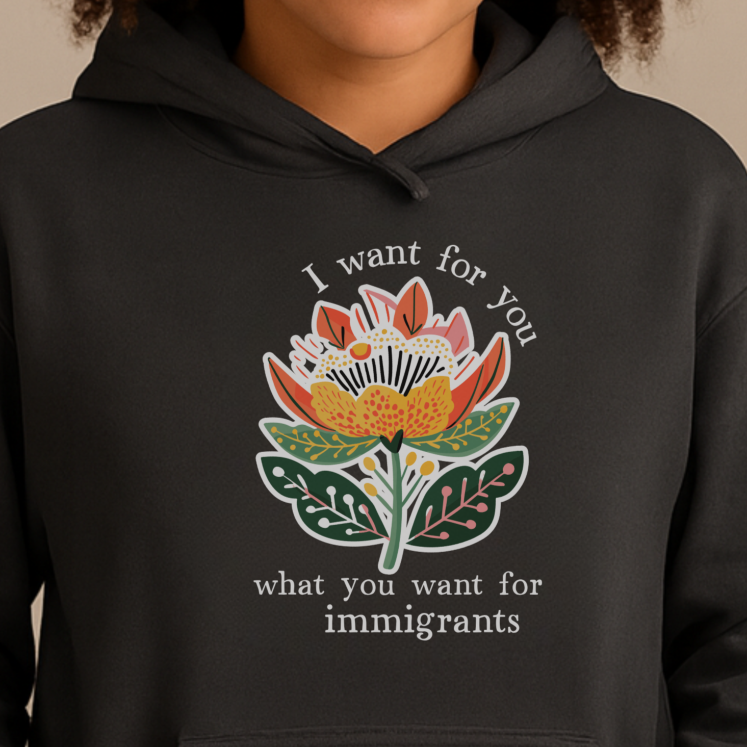 Person wearing a pro-immigration black hoodie with a floral design and text on a beige background