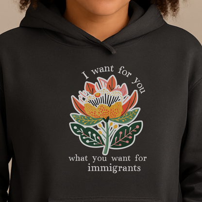 Person wearing a pro-immigration black hoodie with a floral design and text on a beige background