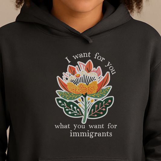 Person wearing a pro-immigration black hoodie with a floral design and text on a beige background